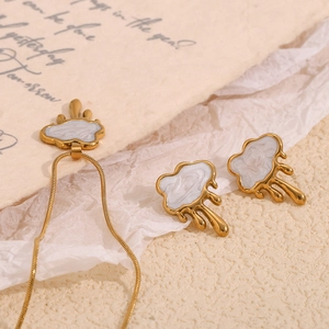Close-up of gold plated cloud tassel shell jewelry set on elegant textured background