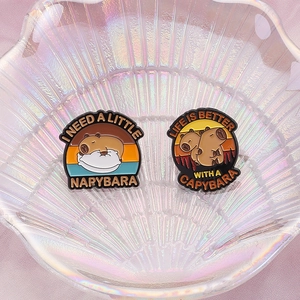 Cute Capybara enamel pins on a pearlescent shell tray with soft lighting detail