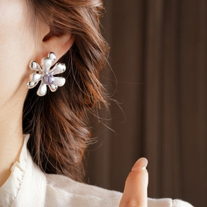 Detail view of a 18k gold-plated floral earring with a soft purple pearl center