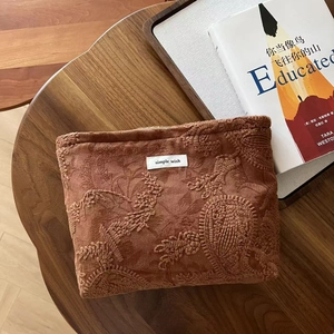 Macro view of vintage camel suede paisley embroidery on the small cosmetic pouch