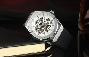 Detail of silver skeleton automatic watch with octagonal bezel and black rubber strap