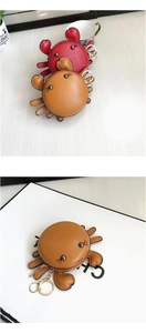Detailed close-up of cute crab-shaped leather coin purses in red and brown with gold keyrings