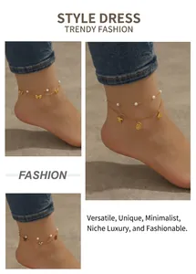 Detail of gold layered anklets with starfish, shell, and butterfly charms on beach sand