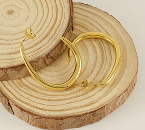 Polished gold U-shaped chunky stainless steel earrings displayed on natural wood