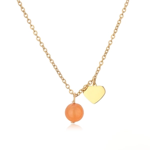 Close-up of golden necklace with a peach pink stone bead and polished heart pendant