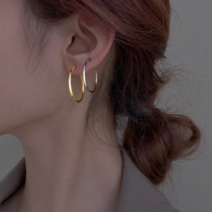 Minimalist large round hoop earrings in gold and silver finish shown on a model