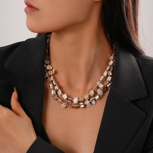 Detail of irregular double-layered shell bead necklace on a model wearing black blazer