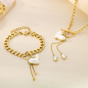 Detailaufnahme des goldenen Titan-Herzschmucksets mit Perlenanhängern und Quastenketten