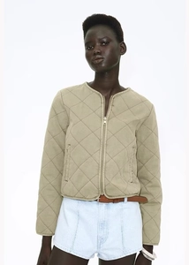 Detail of khaki quilted bomber jacket featuring round neck design and metal zipper closure