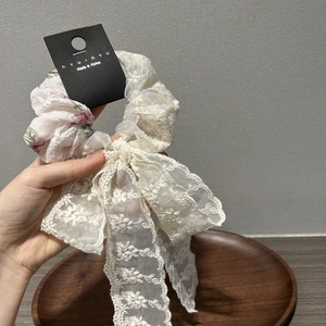 Close-up of floral embroidery lace hair scrunchie with long ribbons on a wooden plate