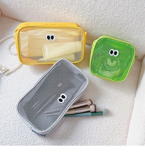 Detail of colorful mesh cosmetic bags with cute eye decor on white faux fur background