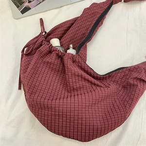 Macro shot of burgundy checkered nylon crossbody bag with zipper and drawstring details