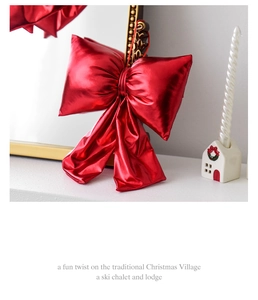 Glossy red satin Christmas bow decoration by a golden mirror and candle holder