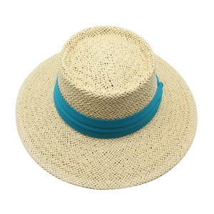 Detailed top view of light beige straw boater hat with vibrant blue ribbon on white background