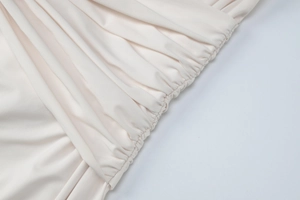 Detailed view of apricot fabric texture featuring elegant ruched seams and smooth material