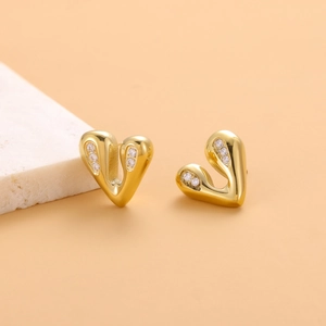 Macro shot of gold heart stud earrings with sparkling white cubic zirconia inlay
