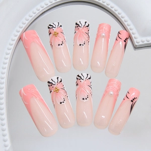 French tip coffin fake nails with pink flower designs and 3D pearls on a mirror