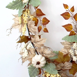 Detailed view of autumn garland featuring white mini pumpkins, berries and fall silk leaves