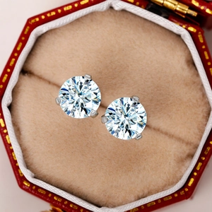 Macro shot of silver crown-set cubic zirconia stud earrings in a red gift box