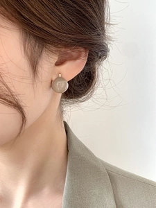Detail of elegant milk tea resin drop earrings with gold hoop on female model