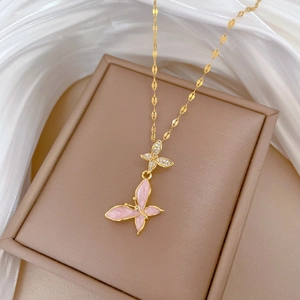 Macro shot of gold butterfly pendant with pink enamel and sparkling zircon inlay details