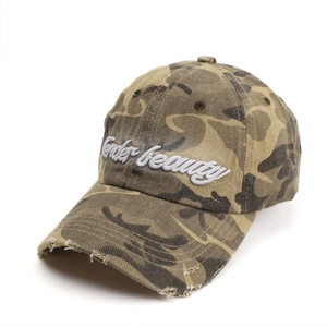 Detailed view of the 3D embroidered Under Beauty text and distressed camo cap brim