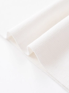 Close-up of premium white ribbed knit fabric showing detailed vertical texture and soft weave