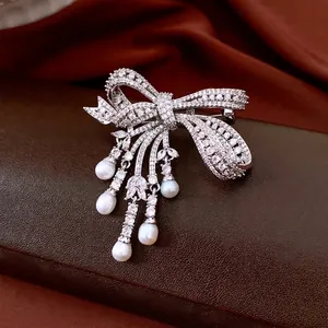 Elegant silver bow brooch with white zircon stones and five dangling teardrop pearls