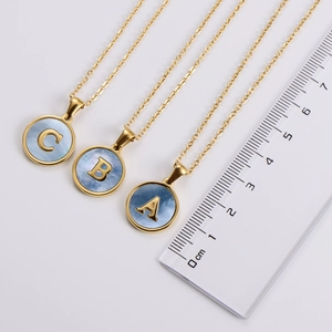 Detail view of 18k gold plated letter pendants with light blue shell inlay and measurement