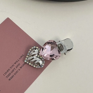 Detail of pink heart-shaped crystal and silver embossed heart on a metal hair clip