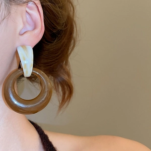 Detail view of vintage resin round earrings in amber brown and milky marble on a model