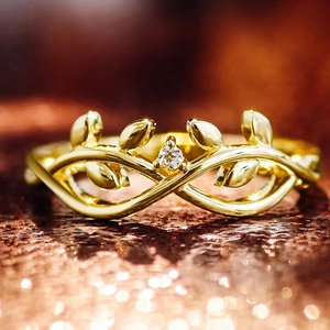 Elegante anillo de oro con diseño de hojas y circón sobre fondo cálido brillante