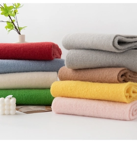 Stack of thick woolen scarves in various colors including blue, red and grey