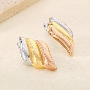 Gros plan détaillé de boucles d'oreilles ondulées tricolores en argent, or et or rose