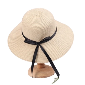 Elegant beige straw sun hat with wide brim and black ribbon bow for beach vacation