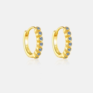 Détail macro de boucles d'oreilles en argent S925 doré avec zircons bleus et poinçon