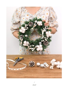 Detailed Christmas wreath featuring cotton, pine cones, and festive ribbons for holiday decor