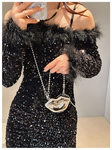Silver lip-shaped metal evening bag with chain strap held by model in sequin dress