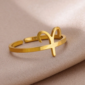 Macro detail of Aries zodiac symbol ring in polished gold finish on silk background