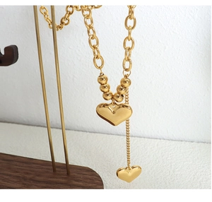 Detail of 18K gold-plated double heart pendants on a chunky beaded link chain necklace