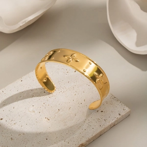 Detail of wide 18K gold plated cuff bracelet with embossed floral texture on stone