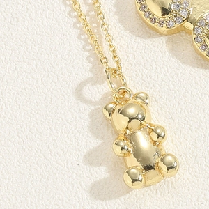 Close-up of golden bear pendant with sparkling zircon and polished fine chain necklace