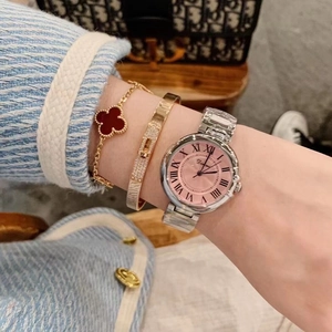 Silver stainless steel watch with pink dial and Roman numerals worn on wrist with bracelets
