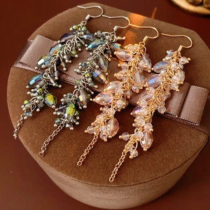 Detail of bohemian crystal tassel earrings in silver and gold displayed on a gift box