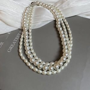 Detailed view of elegant triple-layered pearl necklace with glossy cream-white beads