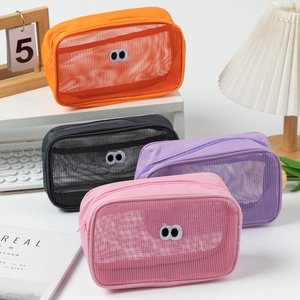 Detail of four colorful mesh makeup bags with eye patches on a desk with accessories