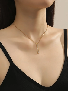 Dettaglio di una collana minimalista in acciaio dorato con ciondolo in conchiglia bianca