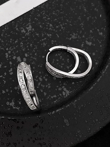 Macro shot of silver dual-layer interlocking earrings with square zircon on dark surface