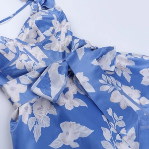 Detail of blue floral satin dress featuring a large bow and glossy fabric texture