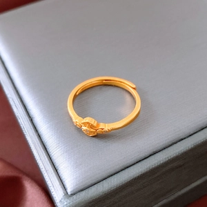 Vue macro d'une bague dorée avec gravure de croix et petite pierre précieuse brillante